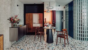 A modern kitchen with a round dining table, two chairs, and a vase of flowers. - Apartament przy MCK (Katowice)