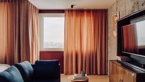 A modern living room with a sofa, a television, and a small table. - Apartament przy MCK (Katowice)