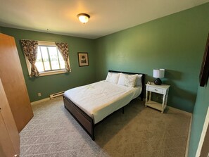A bedroom with a bed, a nightstand, a window with curtains, and a ceiling light.