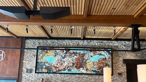 Un interior moderno con un amplio mural de temática animal, vigas de madera en el techo, paredes de piedra y zonas de estar.