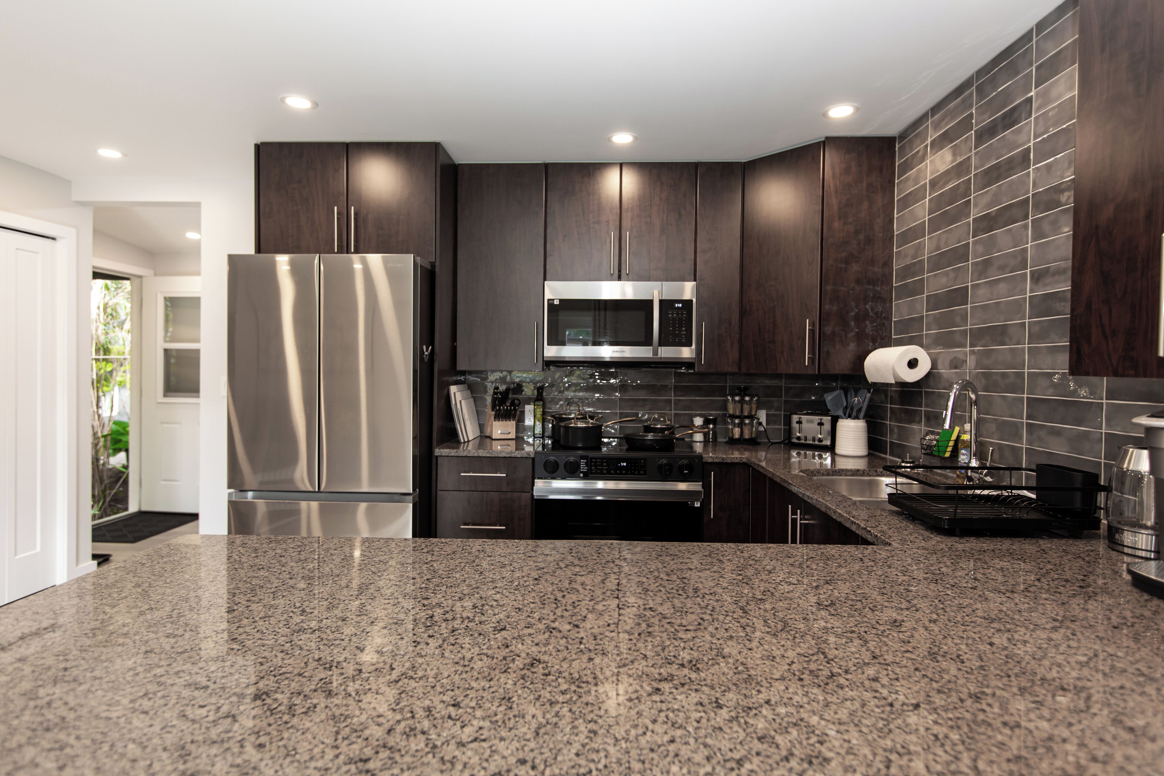 A modern kitchen with dark wood cabinets, stainless steel appliances, and granite countertops.