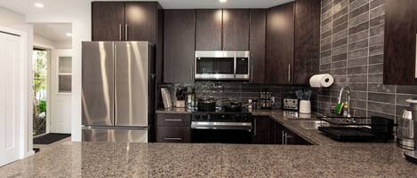 A modern kitchen with dark wood cabinets, stainless steel appliances, and granite countertops.