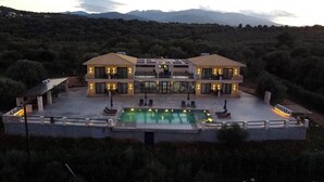 A two-story house with a swimming pool, surrounded by trees and mountains. - New Infinity Pool & Jacuzzi Villa w/Private Chef,perfect for Groups & Families! (SPARTO)