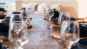 Una mesa de comedor dispuesta con copas de vino y platos, con vistas a las montañas al fondo.