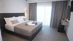 Una habitación de hotel moderna con una cama grande, una mesita de noche, un espejo y una ventana con cortinas.