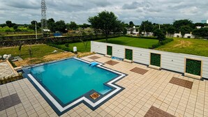A swimming pool with a tiled deck, surrounded by a low wall with green planters.