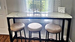 Una piccola zona pranzo con un tavolo bianco e tre sgabelli.