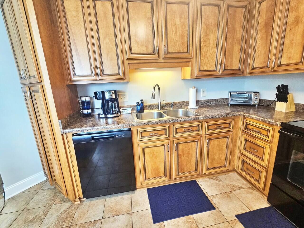A kitchen with wooden cabinets, a dishwasher, a sink, a toaster, and a coffee maker.