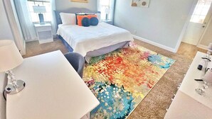 Una camera da letto con un letto, una scrivania e un tappeto colorato.