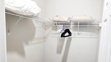 Un petit dressing sans porte, avec un sol foncé et un mur blanc.