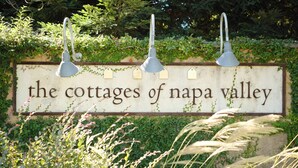 A sign for "The Cottages of Napa Valley" with a rustic design and hanging light fixtures.