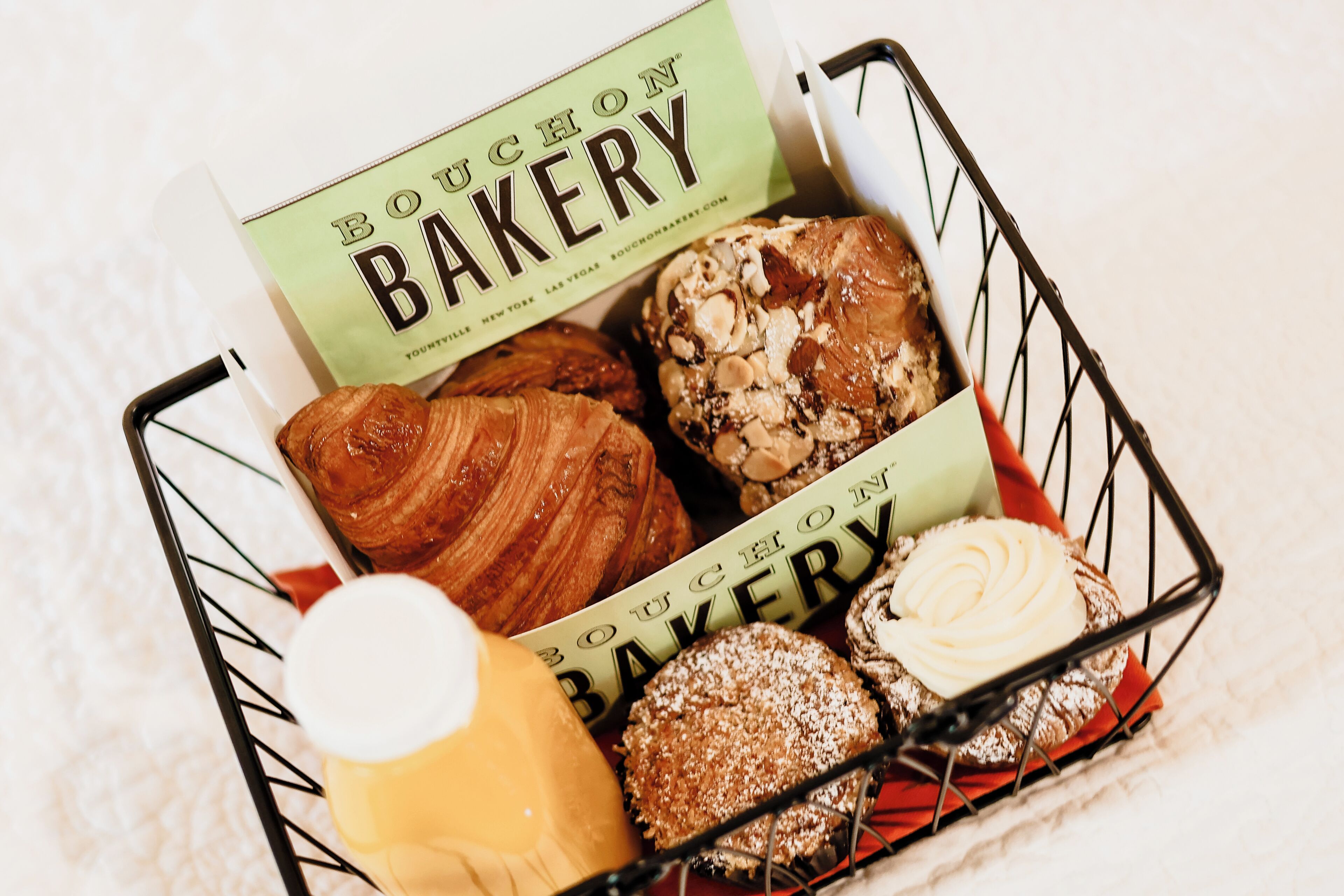 Una cesta con varios pasteles y una botella de bebida, con un rótulo que dice "Bouchon Bakery".