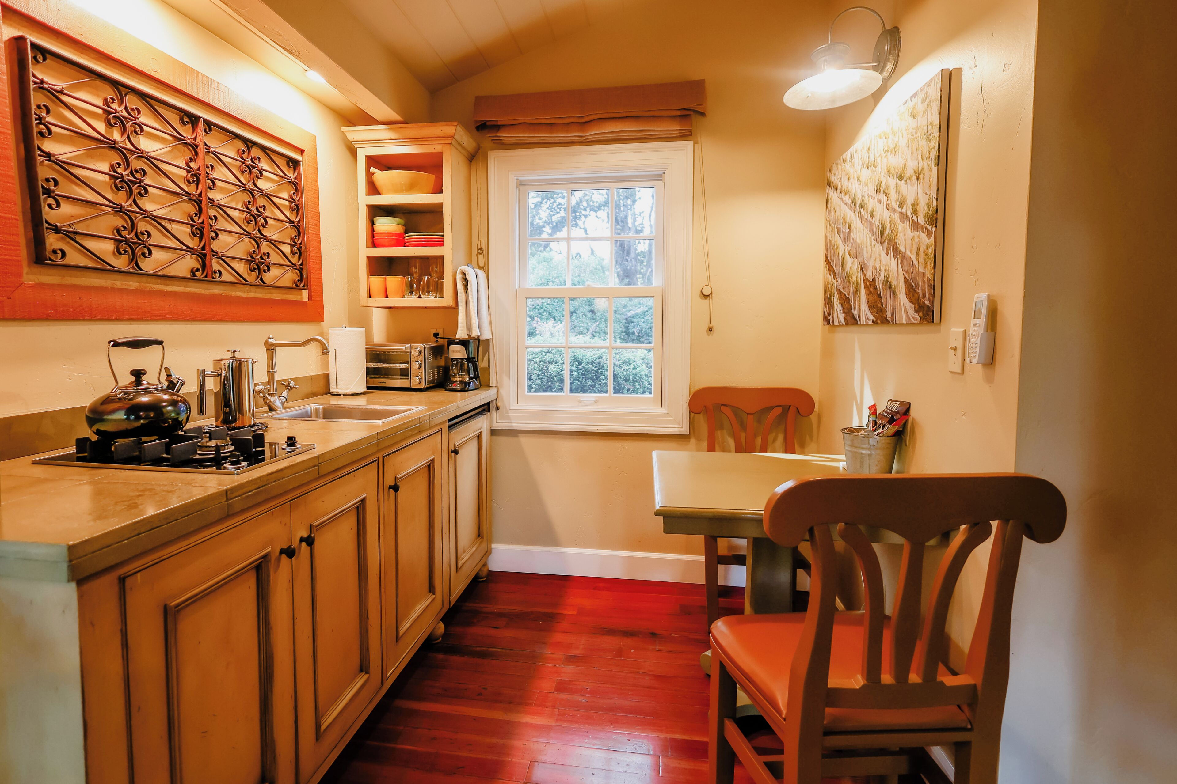 Cocina con armarios de madera, un lavamanos, una estufa y una ventana con vistas al verdor.