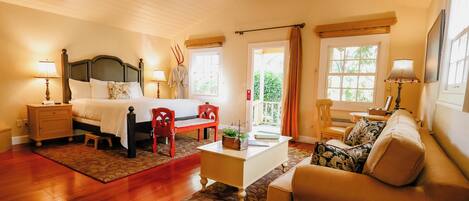 Une chambre bien éclairée, avec un lit, des tables de chevet, une commode, un bureau, une chaise, un canapé et une fenêtre avec des rideaux.