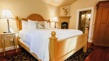 A bedroom with a wooden bed, two bedside tables with lamps, a fireplace, and a wardrobe.