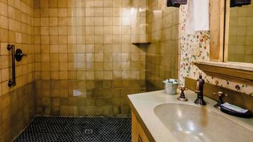 A bathroom with a shower, a sink with a mirror, and a tiled floor.