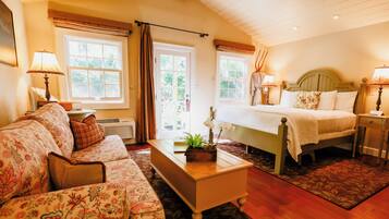 A hotel room with a bed, a sofa, a bedside table, and a window with curtains.