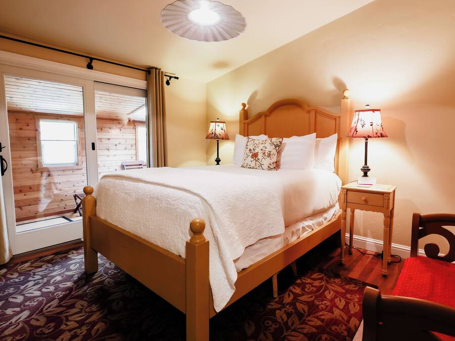 Un dormitorio con una cama de madera, dos lámparas de noche, una mesita de noche y una silla roja.