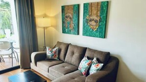 A living room with a sofa, two pillows, a coffee table, and two wall art pieces. - 2-bedroom condo in beautiful Playa Del Coco.  5 minute walk to beach (Guanacaste Province)