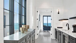 Eine moderne Küche mit großen Fenstern, Meerblick und minimalistischem Design.