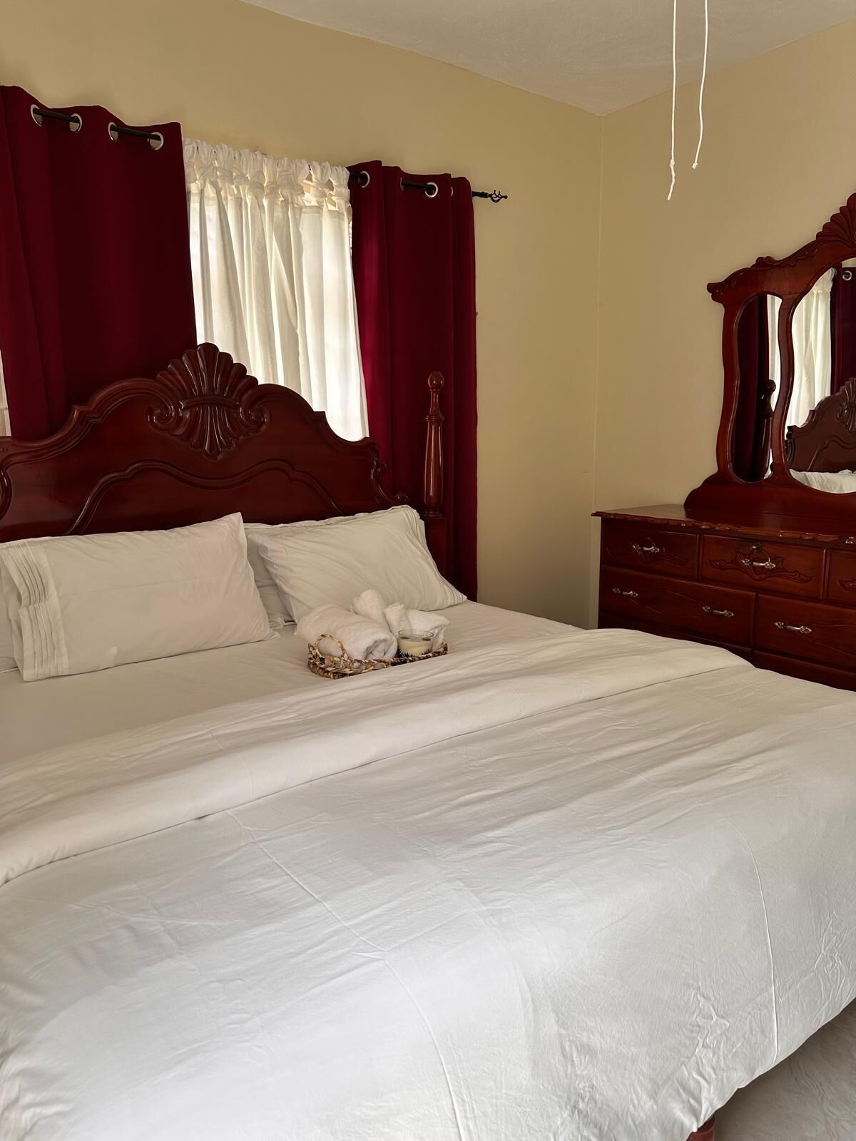 A neatly made bed with white linens, a wooden headboard, and a bedside table with drawers.