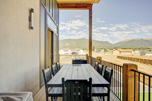 A balcony with a table and chairs, overlooking a mountainous landscape.