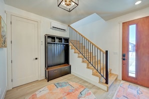 A staircase with wooden steps and a metal railing, leading to a landing with a dark entertainment unit and a light-colored wall.
