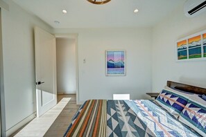 A bedroom with a bed, a painting, and a window.