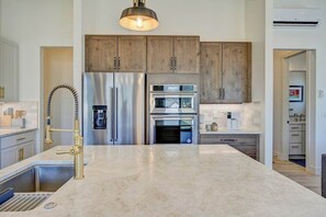 A modern kitchen with stainless steel appliances, a marble countertop, and wooden cabinets.