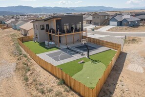 A residential area with houses, a basketball court, and a fenced yard.