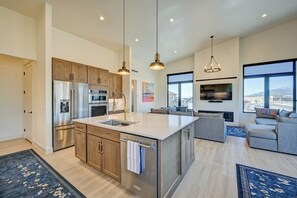 A modern kitchen with stainless steel appliances, wooden cabinets, and pendant lighting.