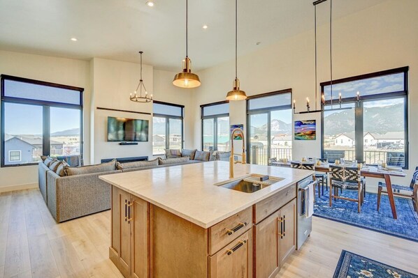 A modern kitchen with a large island, built-in appliances, and a dining area with a view.