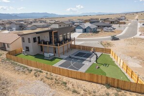 A residential area with modern houses, a basketball court, and a fenced yard.
