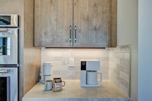 A kitchen with wooden cabinets, a coffee maker, a coffee pot, and a bag of coffee.