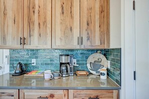 Una cocina con armarios de madera, una cafetera y un plato decorativo con motivos de café.