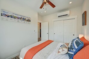 Ein Schlafzimmer mit einem Bett, einem Deckenventilator, einer Wand-Klimaanlage und einer Tür.