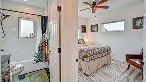 A bedroom with a bed, a ceiling fan, and a window.