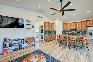 Una cocina moderna con armarios de madera, una isla central con taburetes de bar y un ventilador de techo.