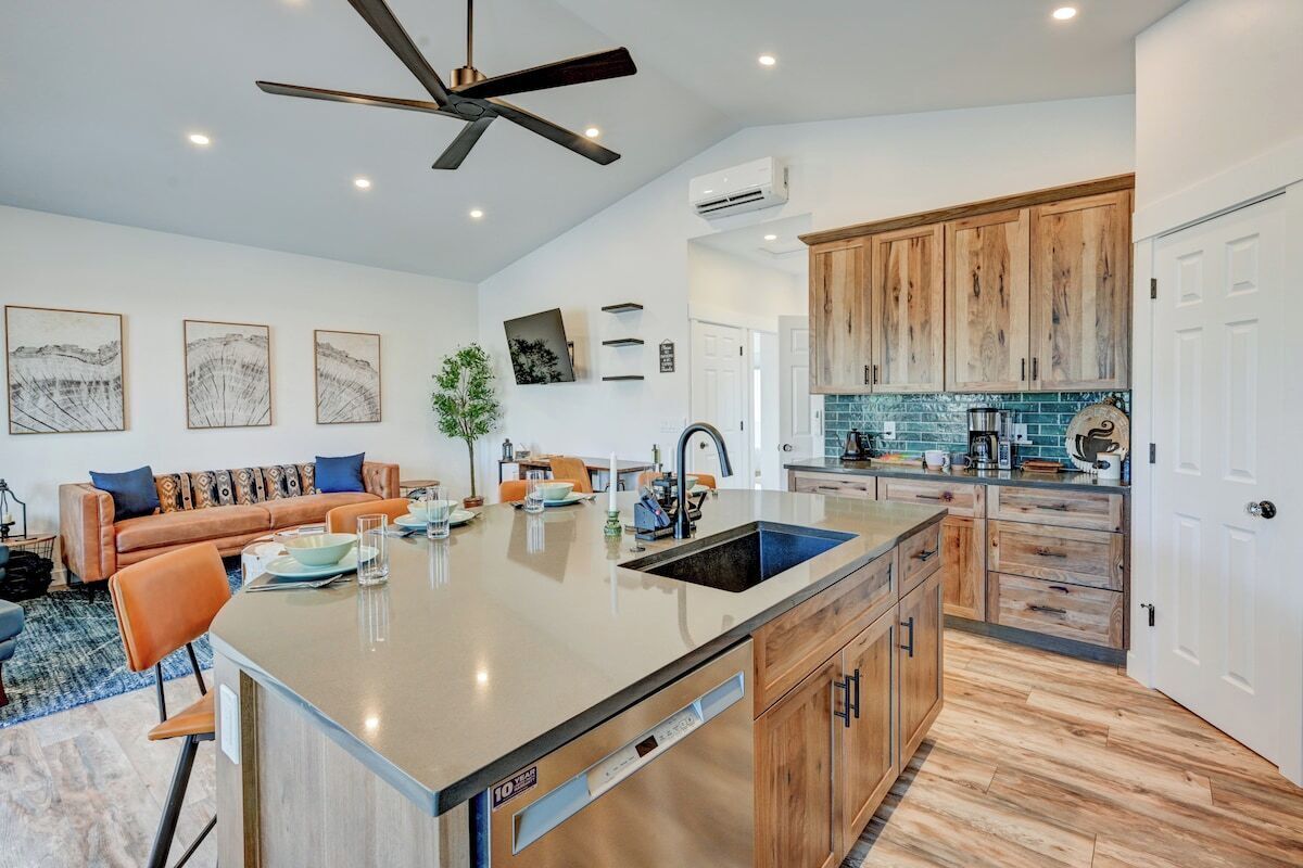 A modern kitchen with a central island, wooden cabinets, and a ceiling fan.