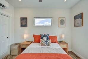 Un dormitorio con cama, dos mesitas de noche, una ventana y obras de arte en las paredes.