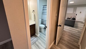 En gang der fører til et badeværelse med toilet, håndvask og bruseforhæng.