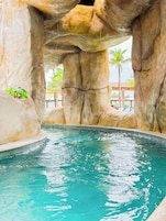 Uma piscina com águas turquesa cristalinas, rodeada por grandes formações rochosas e palmeiras.