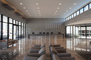 Um hall espaçoso com balcão de recepção, área de estar e grandes janelas com vista para o exterior.
