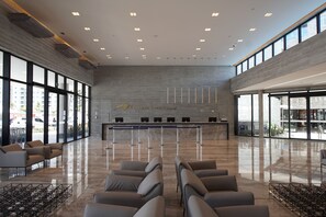 Un vestíbulo amplio con mostrador de recepción, zona de estar y grandes ventanales que ofrecen vistas al exterior.