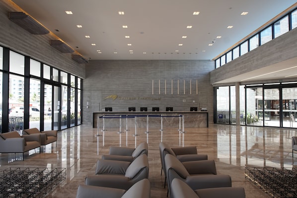 Un vestíbulo amplio con mostrador de recepción, zona de estar y grandes ventanales que ofrecen vistas al exterior.