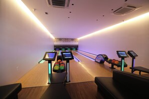 Una bolera con pistas, bolas de bolos y pantallas de puntuación electrónica.