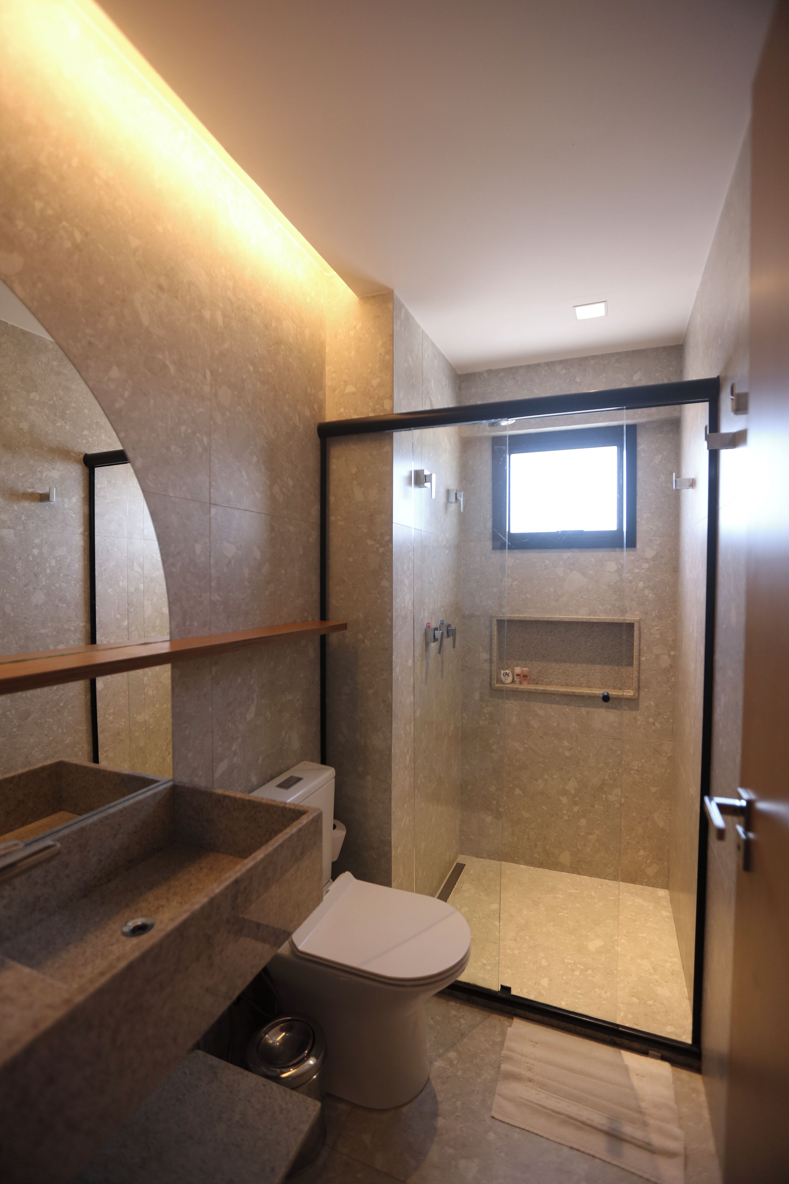 Un baño moderno con ducha de vidrio, inodoro y lavabo con encimera de mármol.