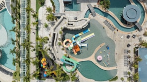 Vista aérea de un resort con múltiples piscinas, toboganes acuáticos y zonas de descanso.