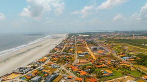 Vista aérea de un pueblo costero con playa, zonas residenciales y edificios comerciales.