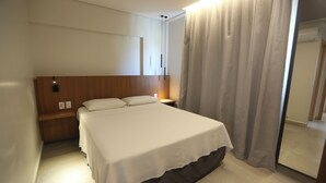 Una camera d'albergo con un letto, un comodino e uno specchio.